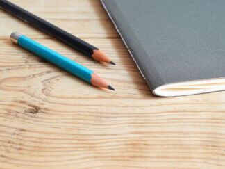 two pencils next to a notebook