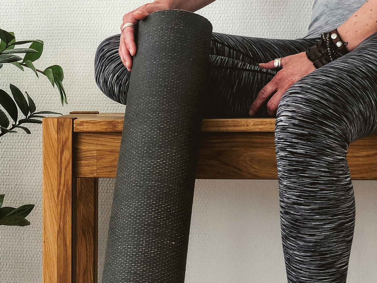 Man holding yoga mat sitting on chair